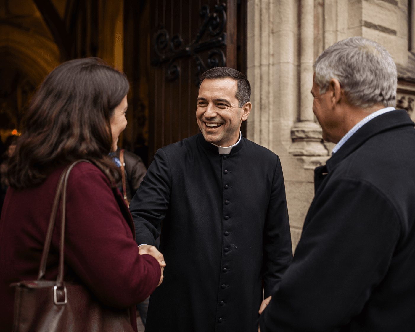 A parish priest greeting parishioners